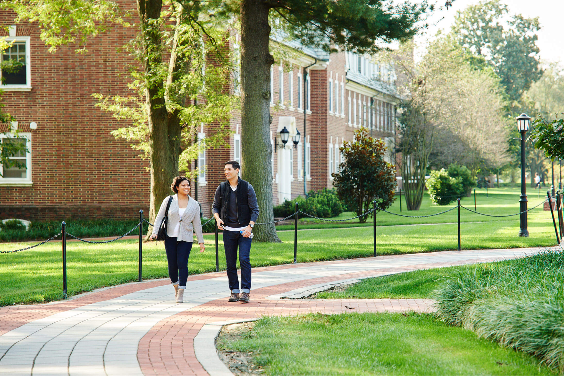 Two students walking and talking on a college campus.